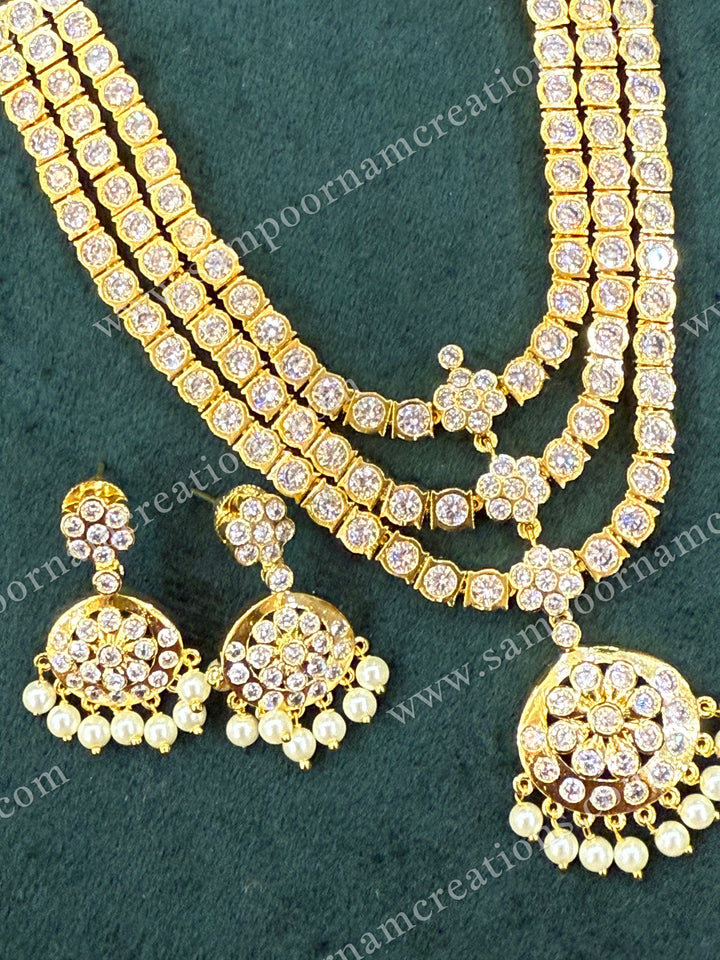 Classic three line white stone adigai with pendant finished with elegant pearl hangings. Comes with matching ear drops  a timeless, traditional neckpiece perfect for sarees.