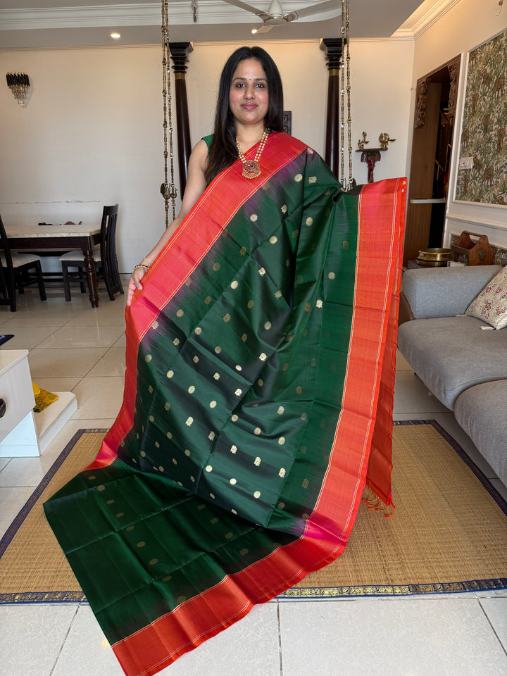 Dark Green with Pinkish Orange , rich zari annam and rudraksh butta in the body , vairaoosi borders and rich Pallu , pure soft silk saree