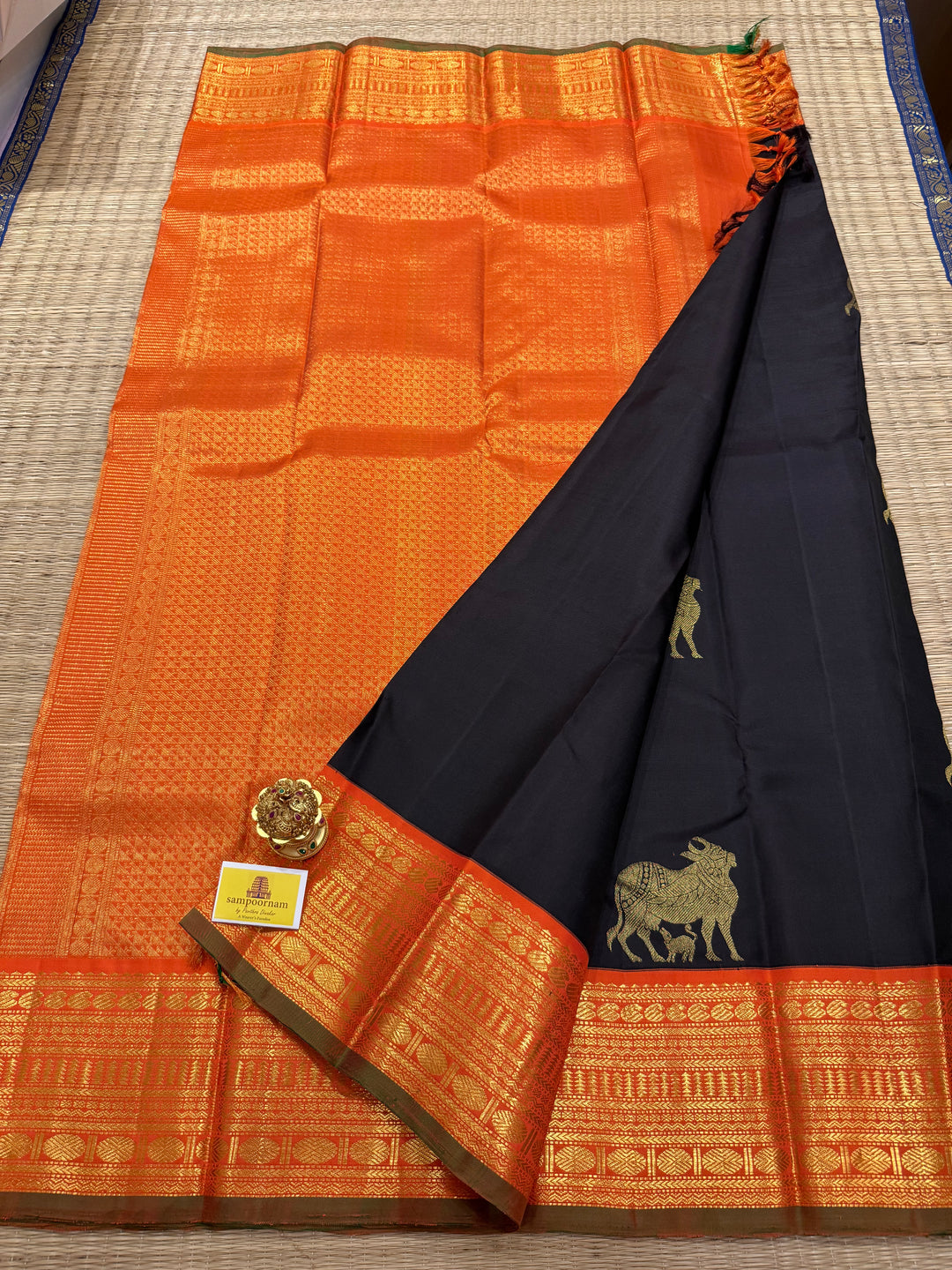 A classic Dark Podi Brown Colour with Fanta Orange Gomatha Cow and Calf Zari Motifs in the Body and Tradition Borders and Rich Pallu Pure Kanjivaram Silk Saree