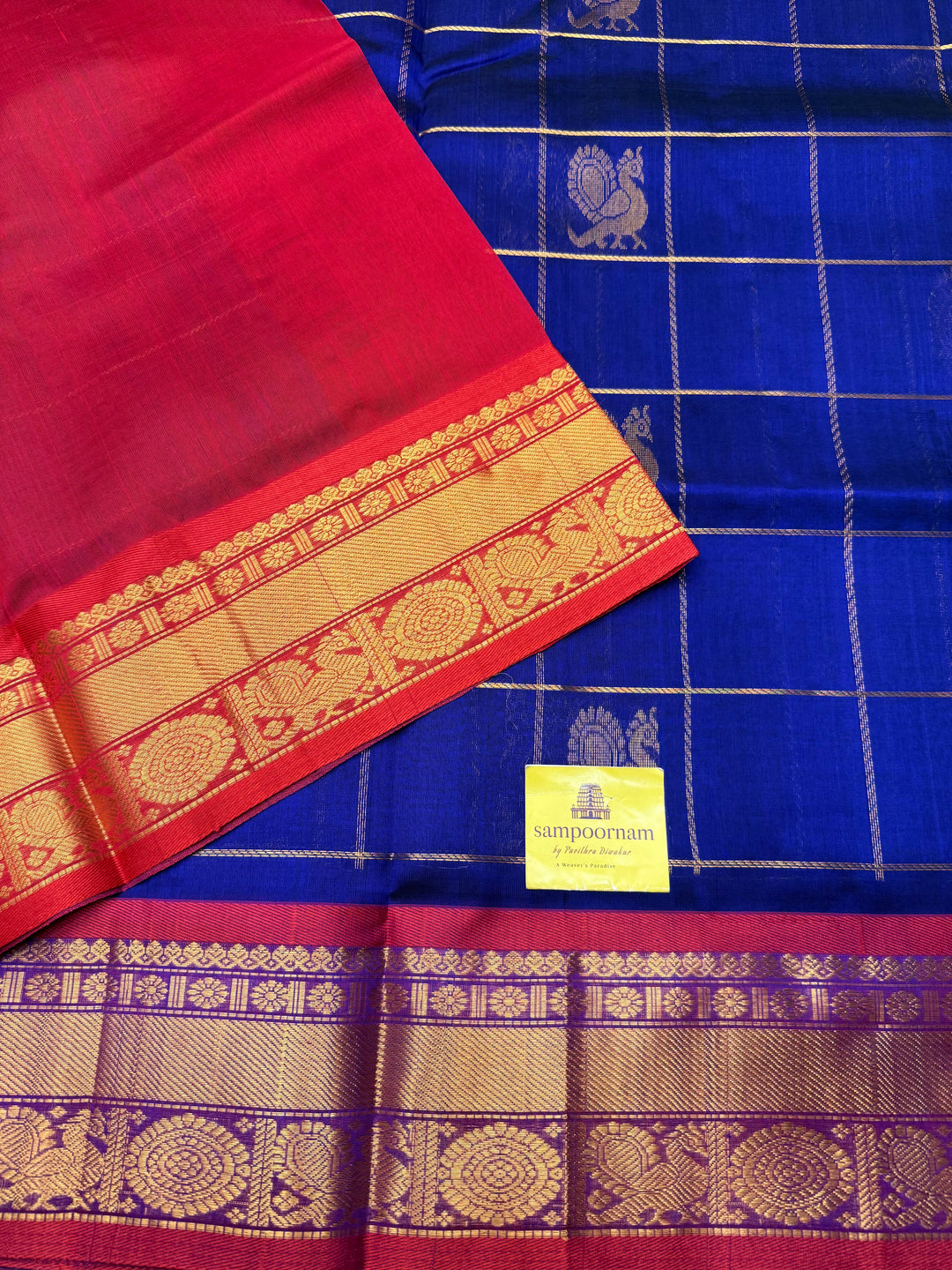 Royal Blue with Red  , rich Zari checks with Mayil Chakram butta in the body , traditional borders and rich Pallu Korvai Silk Cotton Saree