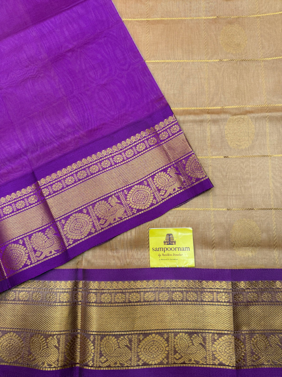 Biscuit with Purple  , rich Zari checks with Mayil Chakram butta in the body , traditional borders and rich Pallu Korvai Silk Cotton Saree