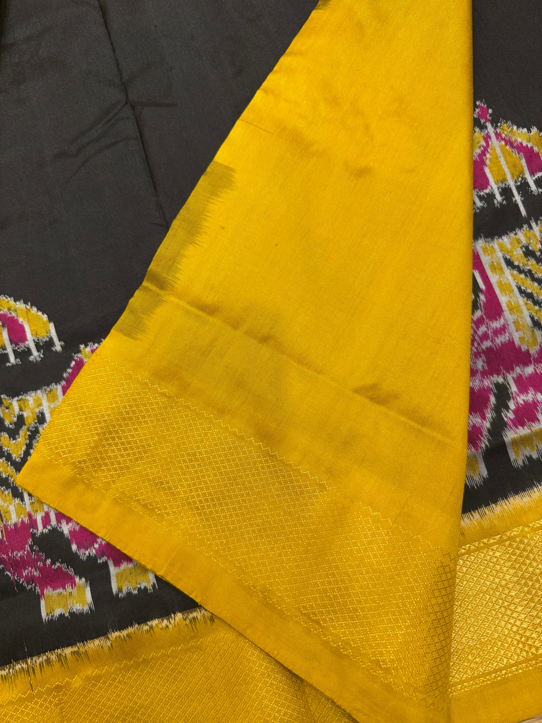 A traditional Black and Mustard combo with Majestic Elephants prints on one side border with traditional border and rich Pallu Pure Pochampally Silk Saree
