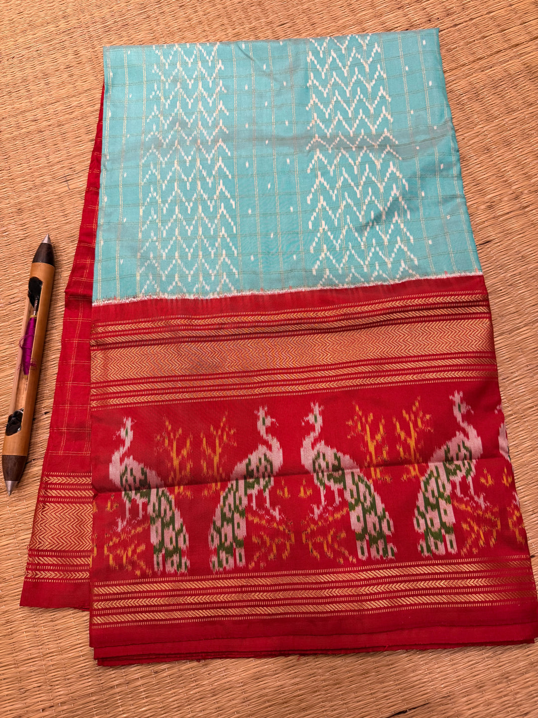 A Gorgeous Pastel Blue with Red saree , with rich Zari checks in the body and one side big Peacock design border and Grand Pallu Pure Pochampally Silk Saree
