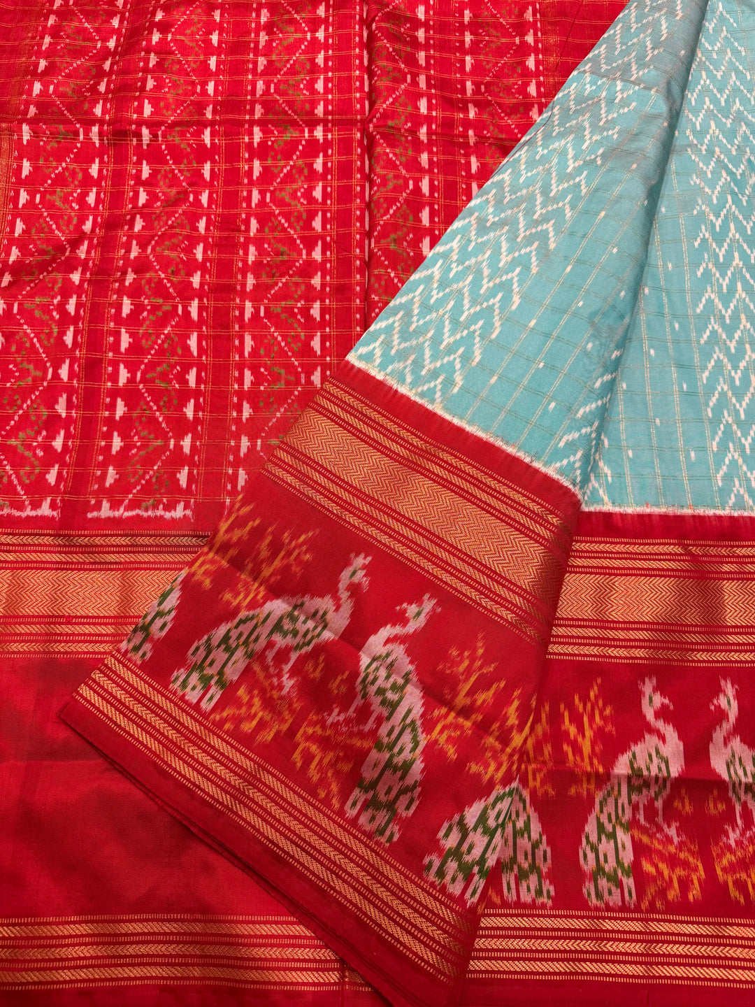 A Gorgeous Pastel Blue with Red saree , with rich Zari checks in the body and one side big Peacock design border and Grand Pallu Pure Pochampally Silk Saree