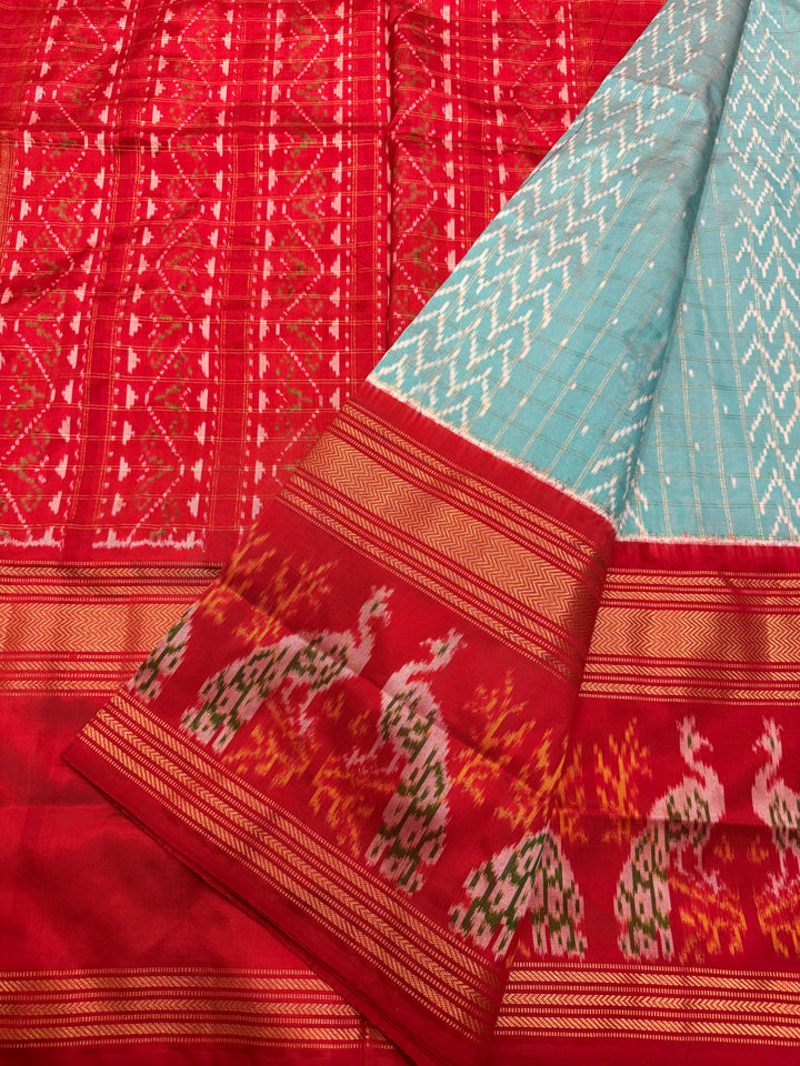 A Gorgeous Pastel Blue with Red saree , with rich Zari checks in the body and one side big Peacock design border and Grand Pallu Pure Pochampally Silk Saree