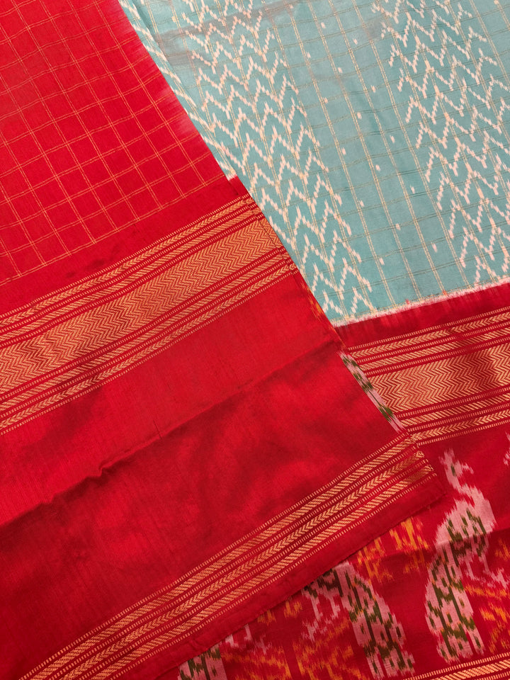 A Gorgeous Pastel Blue with Red saree , with rich Zari checks in the body and one side big Peacock design border and Grand Pallu Pure Pochampally Silk Saree