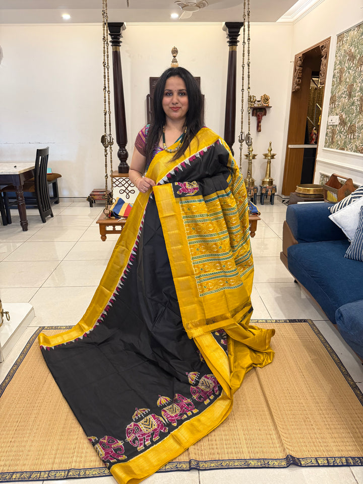 A traditional Black and Mustard combo with Majestic Elephants prints on one side border with traditional border and rich Pallu Pure Pochampally Silk Saree