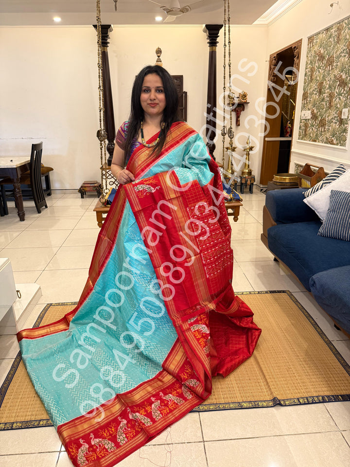 A Gorgeous Pastel Blue with Red saree , with rich Zari checks in the body and one side big Peacock design border and Grand Pallu Pure Pochampally Silk Saree
