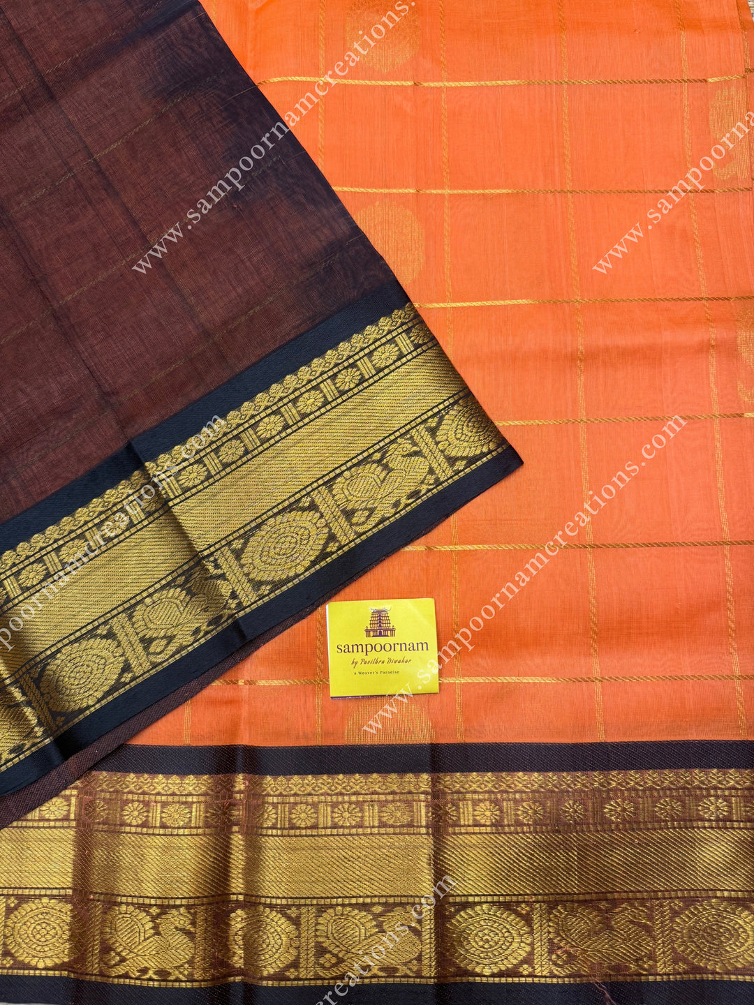 Kanakambaram with Black , rich Zari checks in the body , Mayil and Chakram rich butta in the body ,traditional borders and rich Pallu Silk Cotton Saree