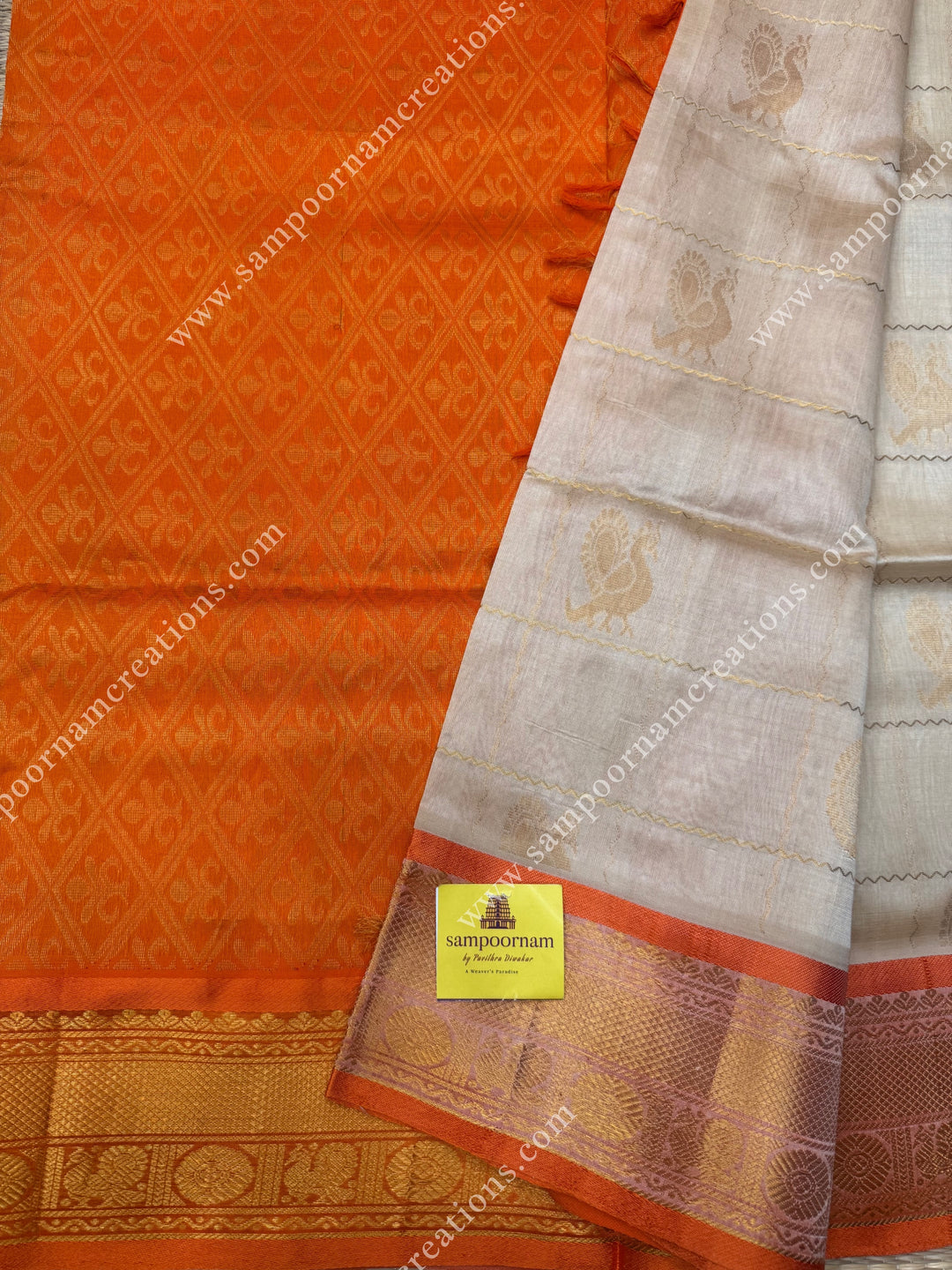 Cream with Orange  , rich Zari checks in the body , Mayil and Chakram rich butta in the body , traditional border rich Pallu Silk Cotton Saree