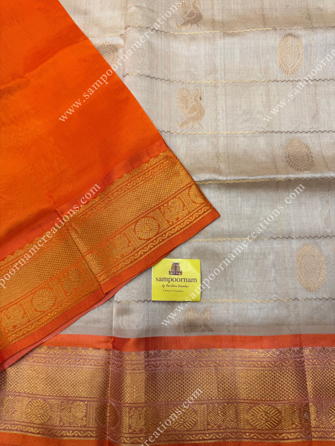 Cream with Orange  , rich Zari checks in the body , Mayil and Chakram rich butta in the body , traditional border rich Pallu Silk Cotton Saree