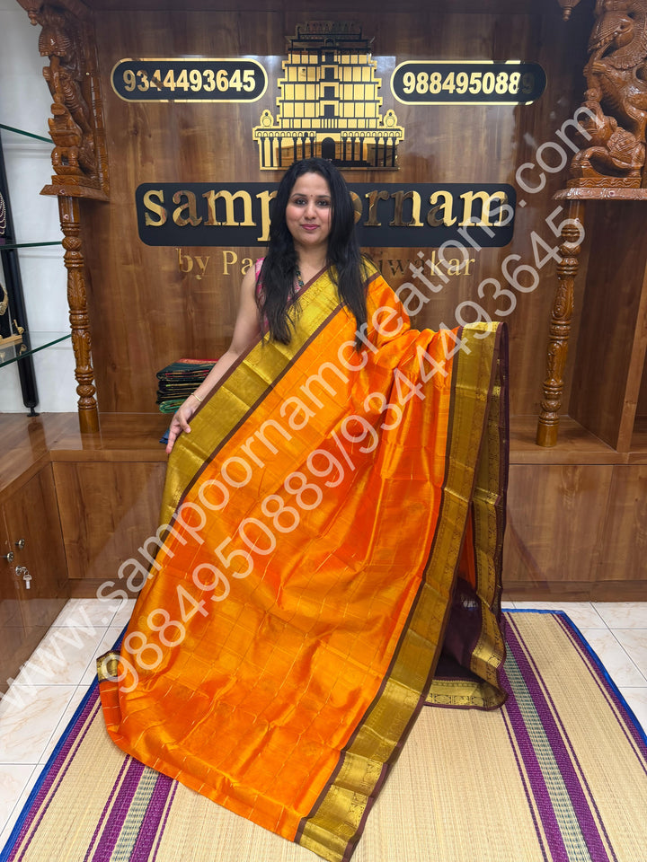 Orange with brown  , Rich Mayil and Chakram butta in the body with Zari Checks , Traditional borders and Rich Pallu Pure Silk Cotton Saree