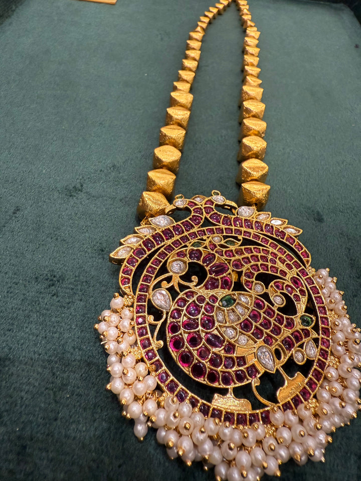 A Piece where tradition gets a bold upgrade , 3D gold beads flows is graduating sizes, Annam pendant detailed with Red Green and White Kemp Stones and delicate adduku white pearls .