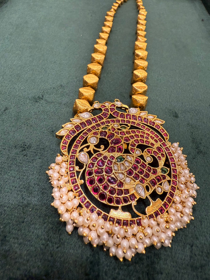 A Piece where tradition gets a bold upgrade , 3D gold beads flows is graduating sizes, Annam pendant detailed with Red Green and White Kemp Stones and delicate adduku white pearls .