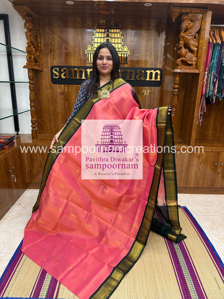 Peachish Pink with Dark Green , rich Zari butta in the body ,traditional boders and rich Pallu Korvai Silk Cotton Saree
