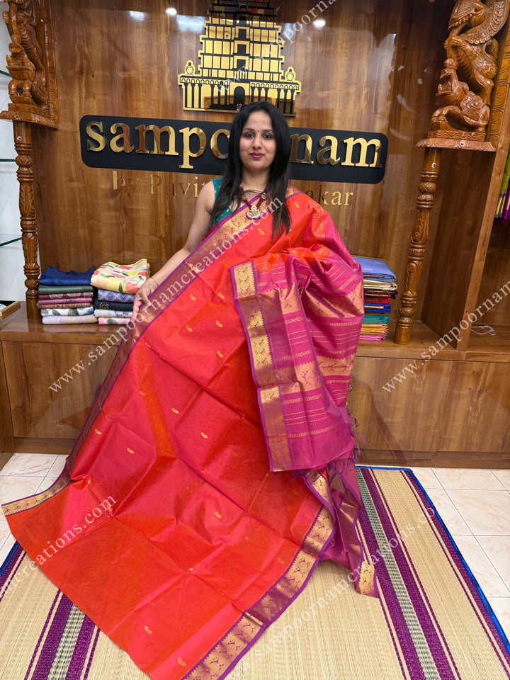 Reddish Orange with Magenta  , Zari butta and Vairaoosi Zari lines in the body, traditional borders  and rich Pallu Silk Cotton Saree