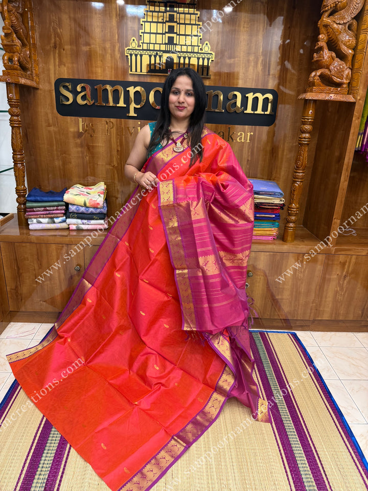Reddish Orange with Magenta  , Zari butta and Vairaoosi Zari lines in the body, traditional borders  and rich Pallu Silk Cotton Saree